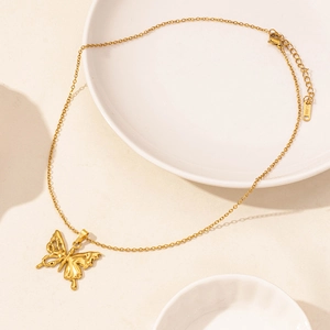 Elegant gold stainless steel butterfly pendant necklace on a minimalist ceramic plate