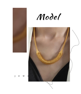 Detailed close-up of golden spiral spring necklace with conical connectors and sleek finish