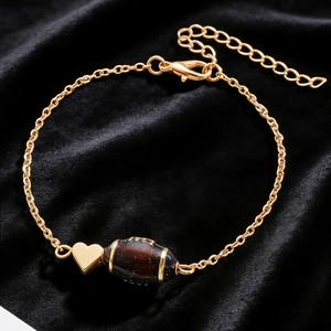 Gros plan d'un collier doré avec pendentif cœur poli et perle sombre scintillante