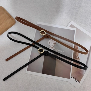 Detailed view of slim leather waist belts in black and brown with chic gold metal buckles