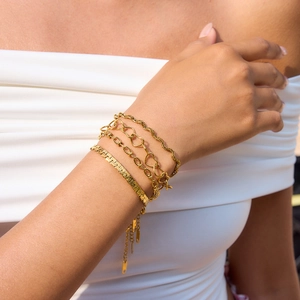Detailed close-up of four assorted gold stainless steel bracelets on a female wrist