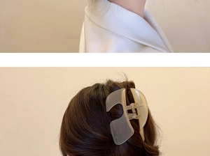 Close-up of a large frosted translucent shark clip securing a bun on dark hair