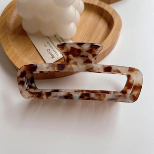 Detail of a rectangular acetate hair claw clip with classic brown and white tortoiseshell patterns