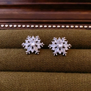 Macro shot of silver snowflake earrings with clear zircons in a dark green velvet box