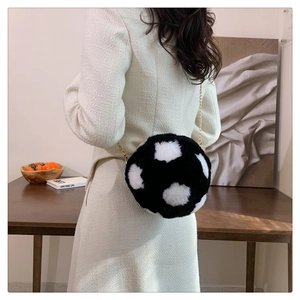 Detail view of soccer-shaped plush crossbody bag with black and white faux fur and gold chain