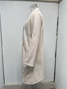Close-up of the wide lapel and side pocket detail on this off-white wool coat