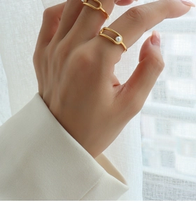 Detail of stacked gold plated rings featuring geometric shapes and white round pearls