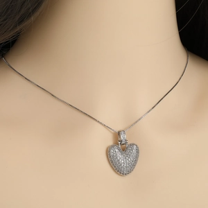 Close-up of a silver heart pendant necklace with shimmering pavé-set zirconias on a model