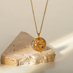 Détail d'un pendentif soleil lune en or 18 carats avec zircons sur une texture pierre