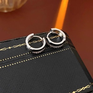 Close-up of minimalist silver zircon earrings with geometric oil-drop design on dark wood