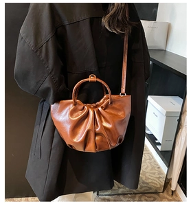 Detailed close-up of brown pleated cloud tote bag with soft leather texture and handle