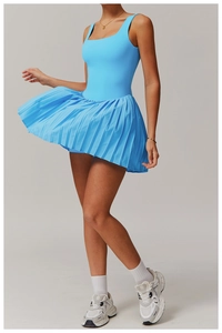 Action shot of light blue tennis dress featuring a square neck and pleated skirt detail