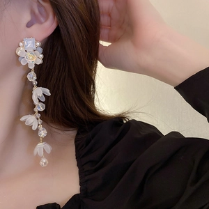 Detail of long floral fringe earrings with white resin petals and clear crystals