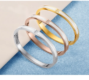 Detailed macro view of tricolor stainless steel bangles with white enamel and zircons