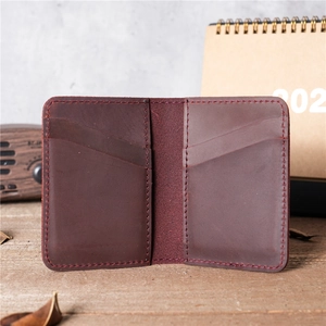 Handmade vintage burgundy leather card holder in a slim bi-fold design on wooden desk