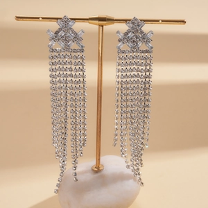 Detail of silver long tassel earrings with sparkling rhinestones on a display stand