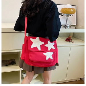 Detail of a red crossbody canvas bag featuring three white star patches and adjustable strap