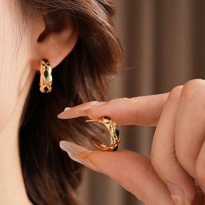 Detail view of vintage diamond pattern C-shaped earrings with red and black stone inlay