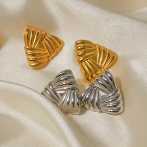 Macro detail of triangle stud earrings with 18k gold and silver woven texture on silk