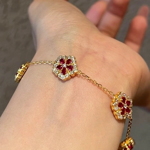 Elegant gold plated flower bracelet featuring red zircon stones and sparkling crystals
