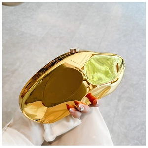 Detail of a gold fluid-shaped clutch bag with high-gloss metallic finish and clasp
