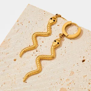 Chic golden snake earrings with textured scales and black bead eyes on stone surface