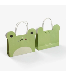 Detail of green frog paper gift bag showing cute cartoon face and white rope handles