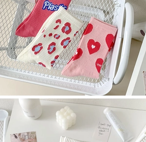 Three-pack cotton crew socks set with pink hearts and flower designs in a white basket