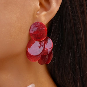 Detail view of bold red layered resin circle earrings worn by a model