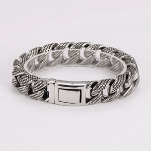Close-up of silver punk chain bracelet with detailed scale patterns and fold-over clasp