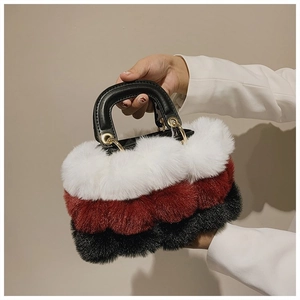 Detail of plush handbag showing white red and black patchwork with black leather handle