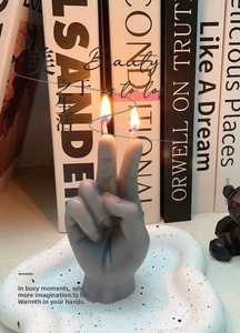 Detail of grey victory gesture candle with double wicks on a speckled ceramic tray