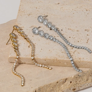Elegant long tassel zircon earrings in stainless steel on a beige textured stone base