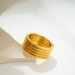 Minimalistischer 18K Gold Schichtring mit glatter Metallstruktur auf Naturstein platziert
