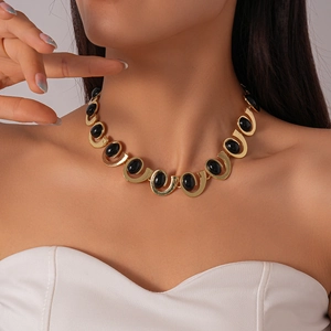 Close-up of vintage gold necklace with black oval stones worn on woman's collarbone