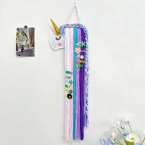 Organisateur de pinces à cheveux licorne en feutre avec pompons colorés sur mur blanc