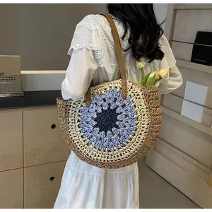 Detail of round paper rope tote with colorful woven pattern and brown leather straps