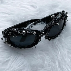 Detailed view of punk sunglasses with silver metal studs and spikes on black frames