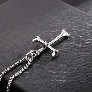 Close-up of silver steel cross pendant with wrap detail on a black textured box