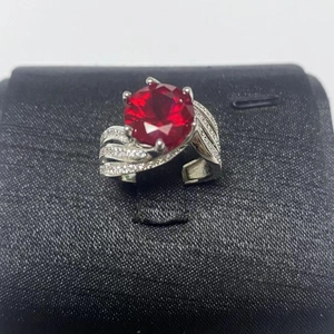 Detailed macro view of silver ring with large red zircon stone and wave micro-pave band
