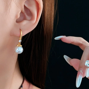 Close-up of 14K gold plated hook earring with sparkling zircon and glossy white pearl