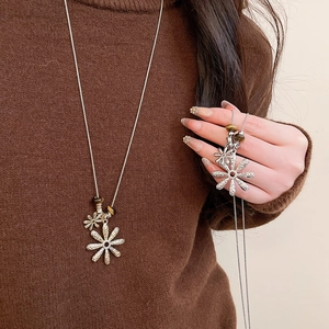 Detailed close-up of tiger eye bead and silver daisy pendant on a long sweater chain