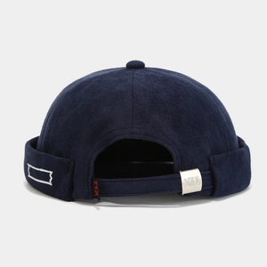 Detail of dark blue docker hat featuring adjustable silver metal buckle and red brand tag