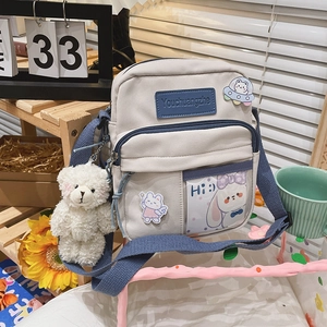 Détail du sac bandoulière en toile avec badges de dessins animés et poche transparente