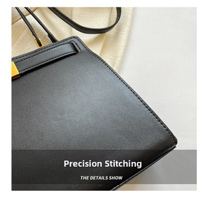 Close-up of precise stitching and matte gold metal hardware on black leather tote bag