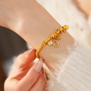 Macro detail of a 24k gold plated bracelet with zirconia charms on a model wrist