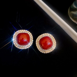 Close-up of luxury red gemstone earrings with diamond halo on black background
