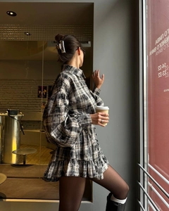 Detail of black and white plaid dress with puff sleeves and ruffled hem design