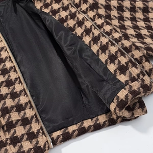 Detail view of brown houndstooth wool fabric with metal zipper and smooth black lining
