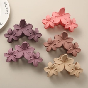 Detail view of five matte floral hair claws in purple, pink, and beige pastel tones